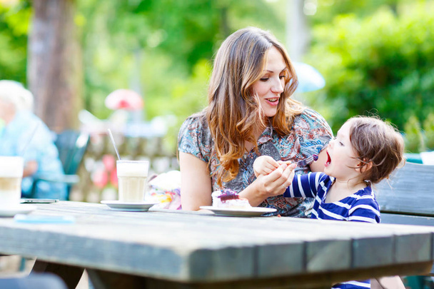 Mother and little adorable kid girl drinking coffee in outdoor c - Foto, Imagen