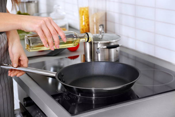 Closeup of woman pouring oil on frying pan - Photo, image