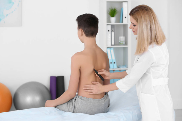 Incorrect posture concept. Physiotherapist examining and correcting boy's back - 写真・画像