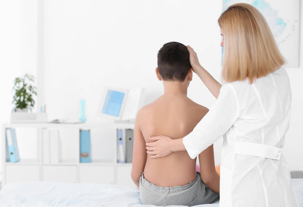 Incorrect posture concept. Physiotherapist examining and correcting boy's back - Fotó, kép