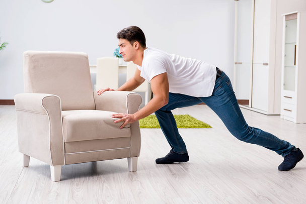 Young man moving furniture at home - Фото, изображение