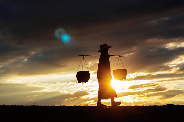 Maanviljelijät kävelevät auringonlaskun aikaan.
. - Valokuva, kuva