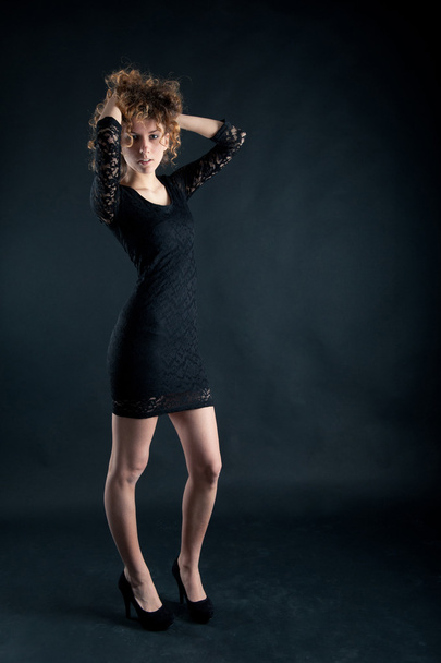 Portrait of beautiful curly girl with black lace dress against dark background - Foto, Bild