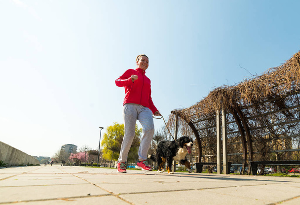 junges hübsches Mädchen läuft mit ihrem Berner Sennenhund im Freien - Foto, Bild