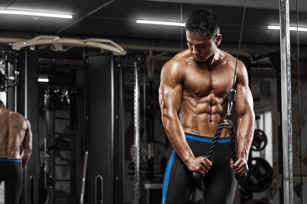 muskulöser Mann, der im Fitnessstudio trainiert und Übungen am Trizeps macht, starker Mann mit nacktem Oberkörper - Foto, Bild