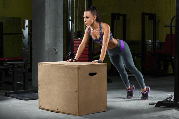 Fitness woman doing push-ups on crossfit box in gym. Athletic girl workout - Photo, Image