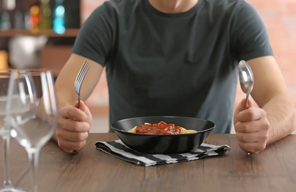 Young man eating pasta at table - Zdjęcie, obraz