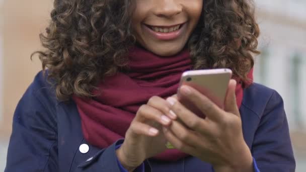 Young multiracial woman browsing images on smartphone, chatting with friend - Filmmaterial, Video
