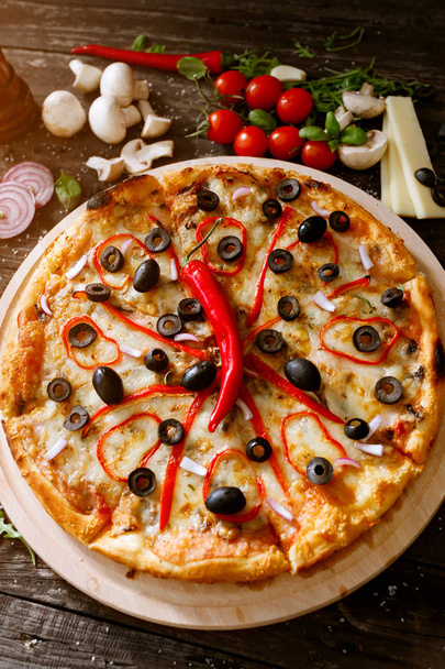 Pizza de queijo com pimenta vermelha fresca e ingredientes na mesa
 - Foto, Imagem