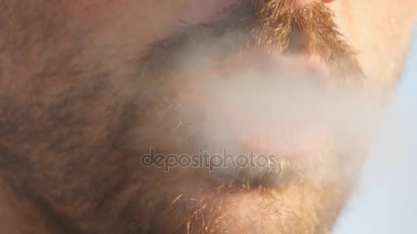 Közeli kép a fiatalember száj cigaretta a dohányzás, füst lélegezzük be, rossz szokás, gyógyszerek. Férfi száj kültéri füstöt fúj - Felvétel, videó
