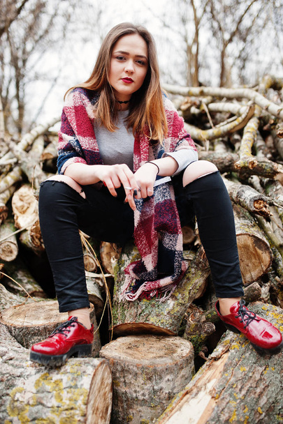 Young girl smoking cigarette outdoors background wooden stumps.  - Φωτογραφία, εικόνα