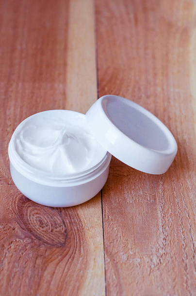 Absoluut witte pot met crème op een ruwe houten achtergrond - Foto, afbeelding