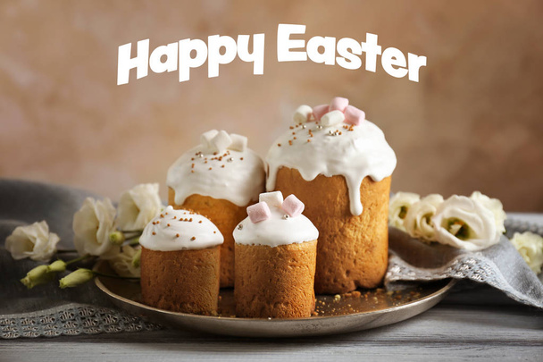 Tray with sweet cakes on wooden table. Text HAPPY EASTER on background - Фото, изображение