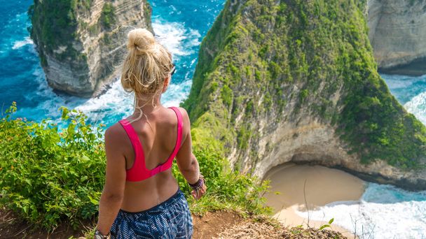 Girl on Cliff at Manta Bay or Kelingking Beach, Nusa Penida Island, Bali, Indonesia - 写真・画像