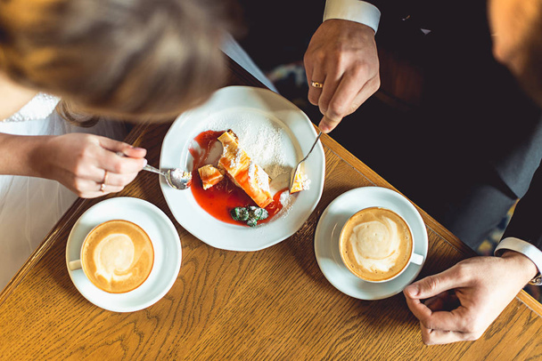 gli sposi bere caffè e mangiare torta in un caffè al tavolo di legno
 - Foto, immagini