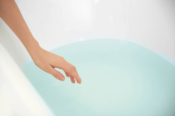 Female hand determining temperature of water - Foto, Imagen