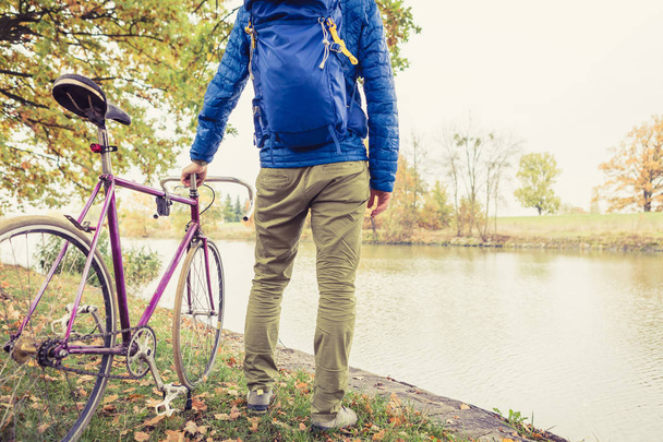 Homem com bicicleta de estrada olhando para a vista do rio no parque
 - Foto, Imagem
