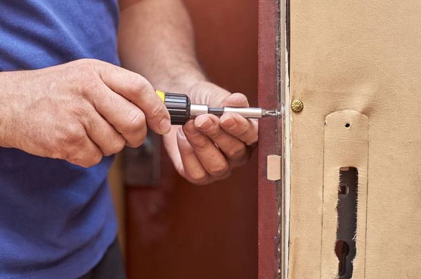 homem fixando uma fechadura na porta velha
 - Foto, Imagem