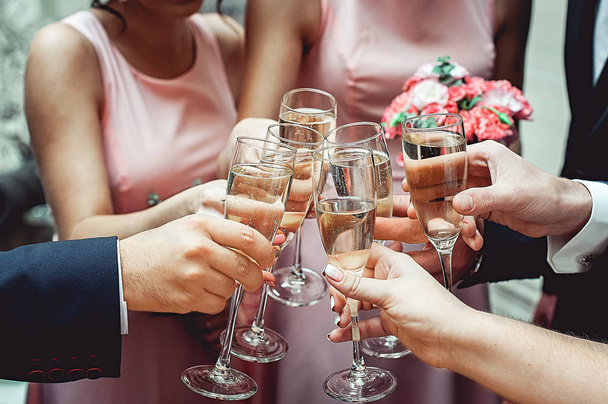 Οι άνθρωποι κρατούν στα χέρια ποτήρια με λευκό κρασί. γαμήλιο πάρτι. - Φωτογραφία, εικόνα