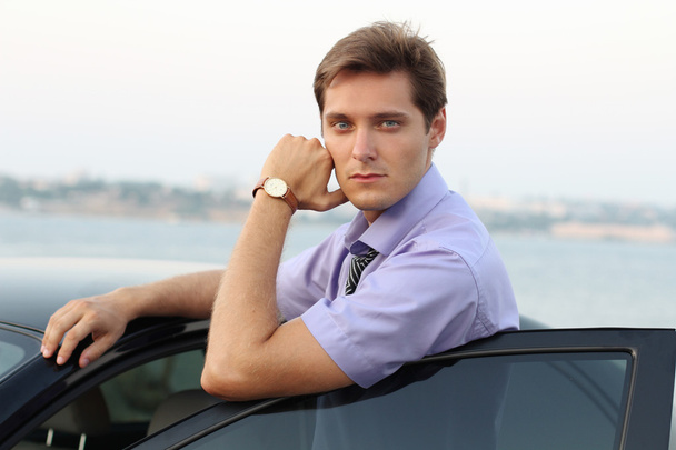 Relaxing young handsome man on car background, outdoor - Fotó, kép