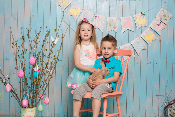 İki küçük childs, oğlum, kız kardeşi ve kız kardeşi ile birlikte parlak yerde oturan tavşan mavi elbise Paskalya, yumurta, şenlikli ruh, duygu ve gülümseme sürpriz tatil kutlaması - Fotoğraf, Görsel