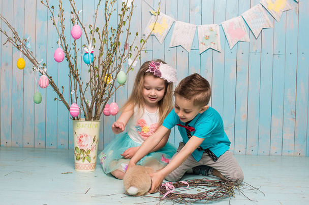 İki küçük childs, oğlum, kız kardeşi ve kız kardeşi ile birlikte parlak yerde oturan tavşan mavi elbise Paskalya, yumurta, şenlikli ruh, duygu ve gülümseme sürpriz tatil kutlaması - Fotoğraf, Görsel