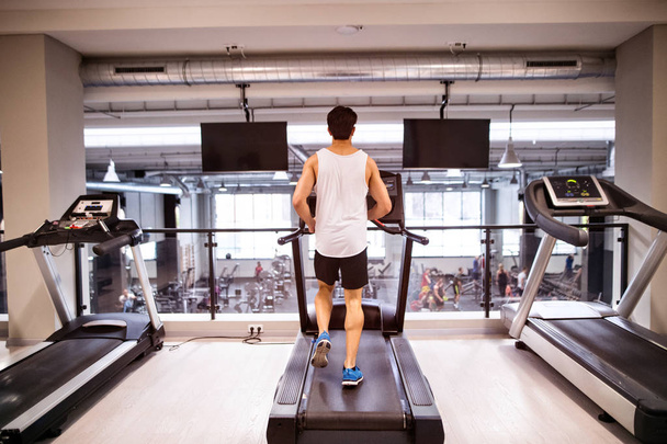 Young fit hispanic man in gym running on treadmill. - 写真・画像