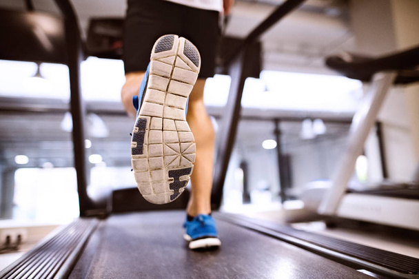 Unrecognizable fit hispanic man in gym running on treadmill. - 写真・画像