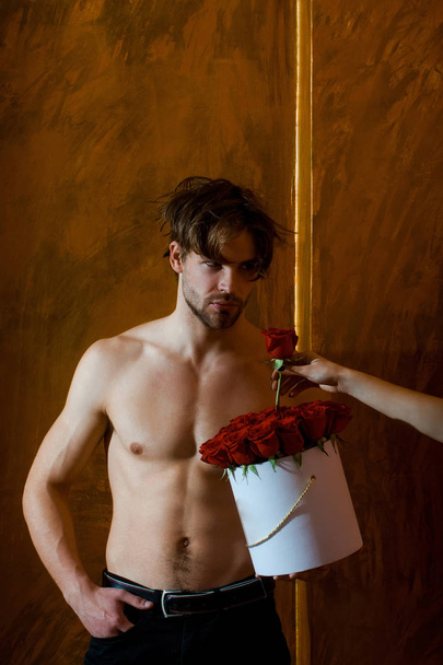 bearded muscular man with sexy body holds red rose box - Foto, afbeelding