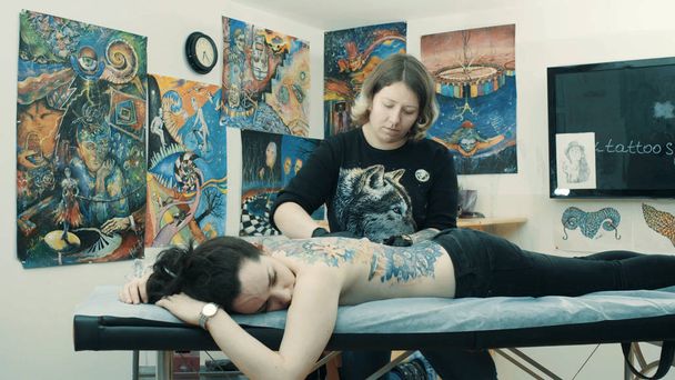 Tatuaje haciendo un tatuaje en la espalda de la chica
 - Foto, imagen