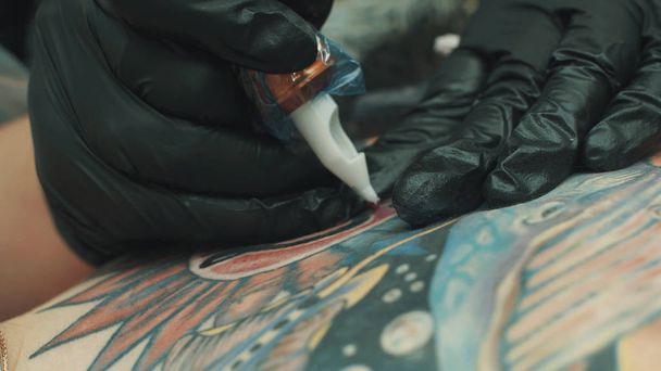 Татуировщик делает татуировку на спине девушки
 - Фото, изображение