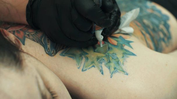 Tatuaje haciendo un tatuaje en la espalda de la chica
 - Foto, Imagen