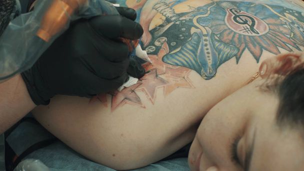 Tatuaje haciendo un tatuaje en la espalda de la chica
 - Foto, imagen