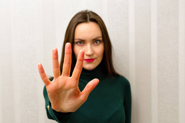 Piękna młoda kobieta, Dokonywanie znak stop z jej ręką uniesioną do góry patrząc na kamery - Zdjęcie, obraz