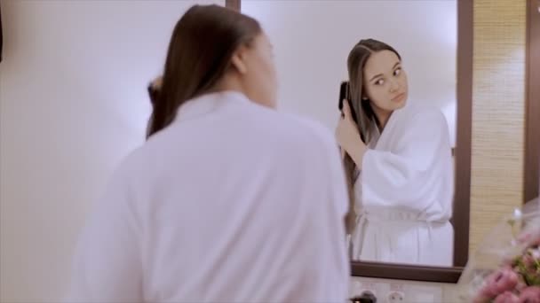 The girl is combing her hair. - Video