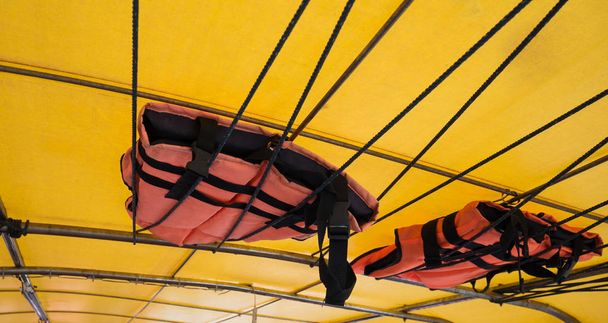 オレンジ色のライフ ジャケットやライフベスト屋根ボートに掛かっています。ボートの転覆したコンセプト. - 写真・画像