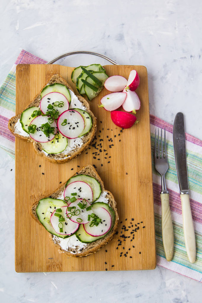 Sandwich with cucumber and radishes on a wooden board - Photo, image