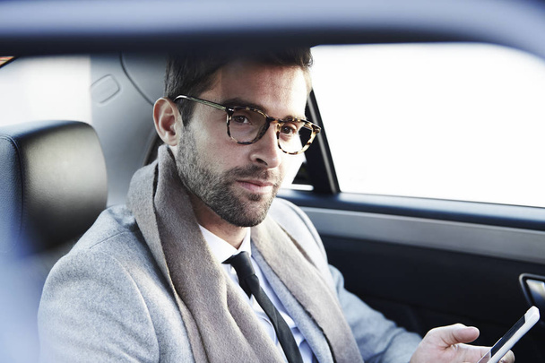 Man in eyeglasses with phone in car  - Foto, imagen
