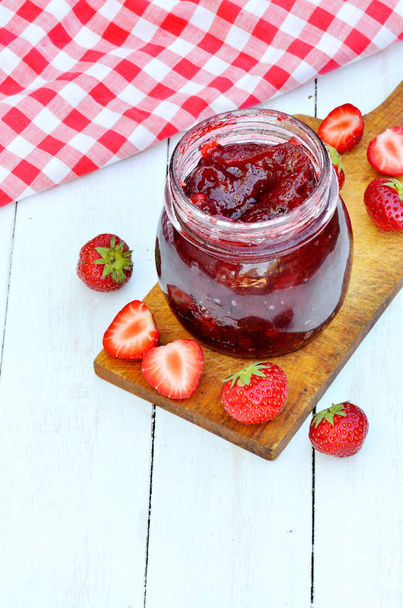 Tarro de mermelada de fresa y fresas frescas en mesa blanca
 - Foto, Imagen
