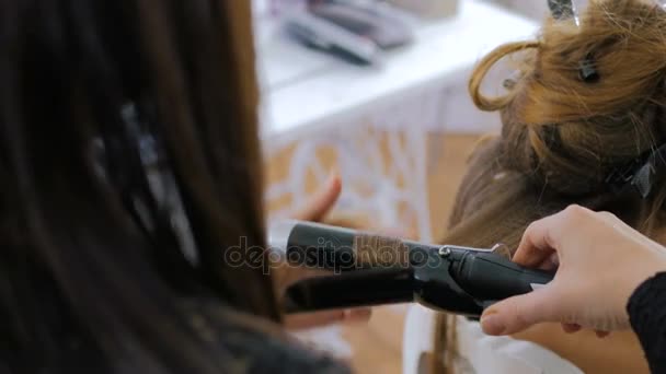 Profesjonalny salon fryzjerski robi fryzurę dla kobiety - Dokonywanie loki - Materiał filmowy, wideo