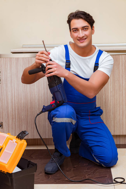 Young repairman working at the kitchen - Photo, Image