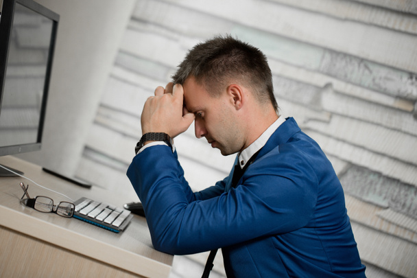 Втомлений бізнесмен на робочому місці в офісі тримає голову на руках. Сонний працівник рано вранці після нічної роботи. Перевантаження, помилка, стрес, припинення або концепція депресії
 - Фото, зображення