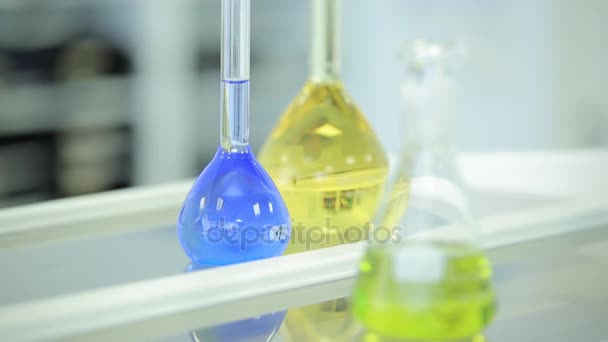 laboratoriumglaswerk met kleur vloeistof en reflectie. reageerbuisjes en kolven met groene en blauwe vloeistof in een laboratorium. Groene en blauwe kolf in laboratorium. Vloeistof in laboratorium kolven. Wetenschappelijke - Video