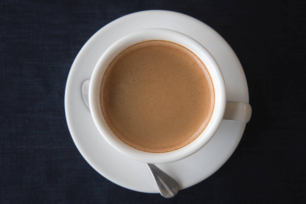 Fehér csésze kávét sötét kék háttér - Fotó, kép