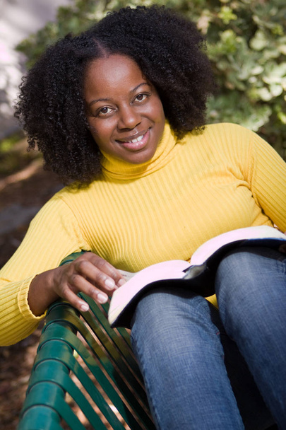 African American woman reading outside in nature. - Фото, изображение