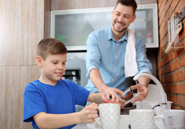 Dad and son doing the washing up in kitchen - Фото, зображення