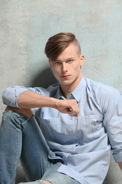 Handsome young man sitting near textured wall - Foto, Imagem