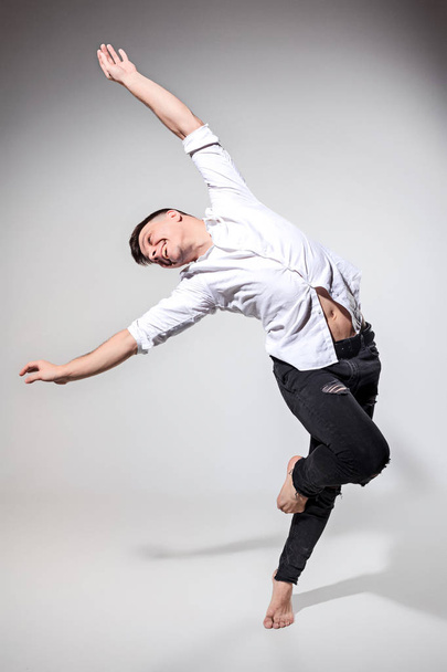 The young man dancing on gray - Valokuva, kuva