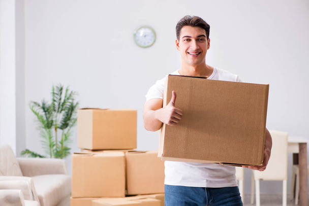 Young man moving boxes at home - Fotó, kép