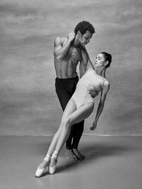 Couple of ballet dancers posing over gray background - Foto, Imagen